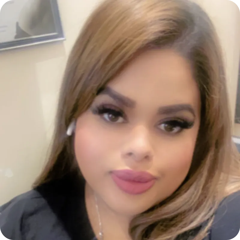 Close-up portrait of a woman with long light brown hair, wearing a black top and white wireless earbud.
