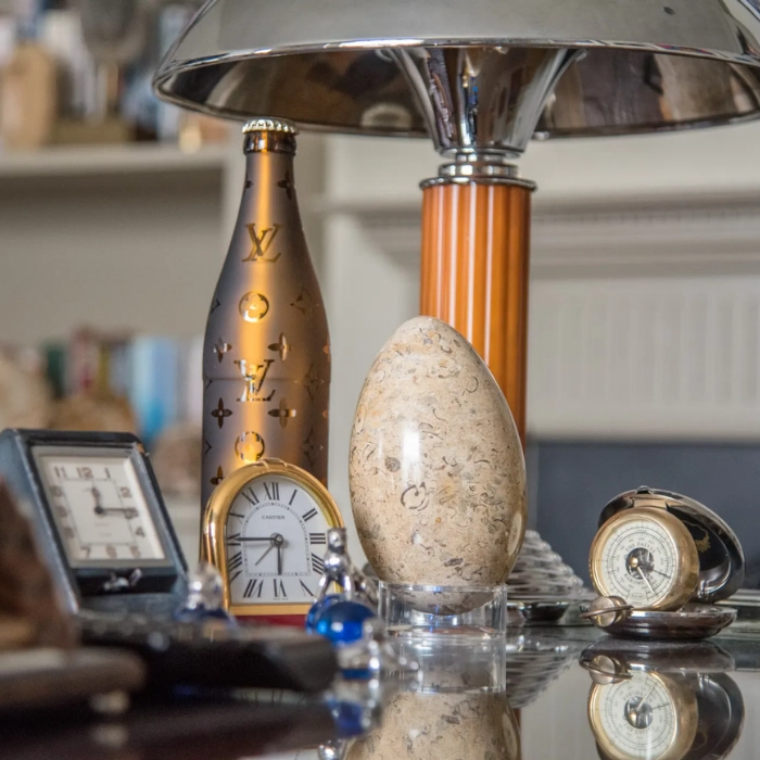 A table with a series of trinkets including clocks and a lamp