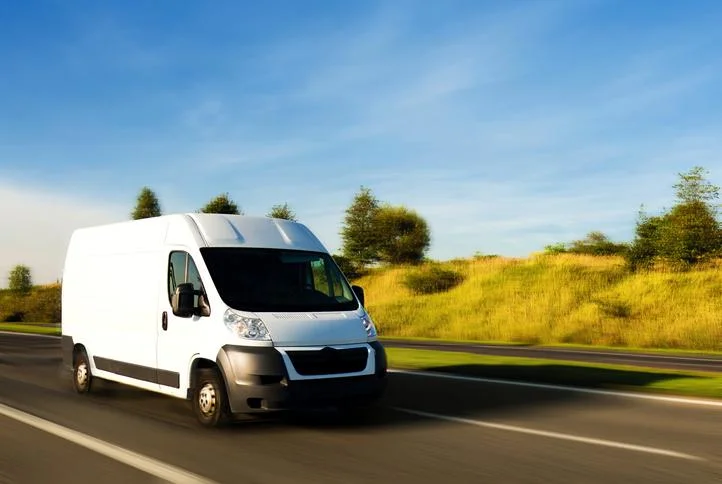 White cargo van driving on a highway at sunset
