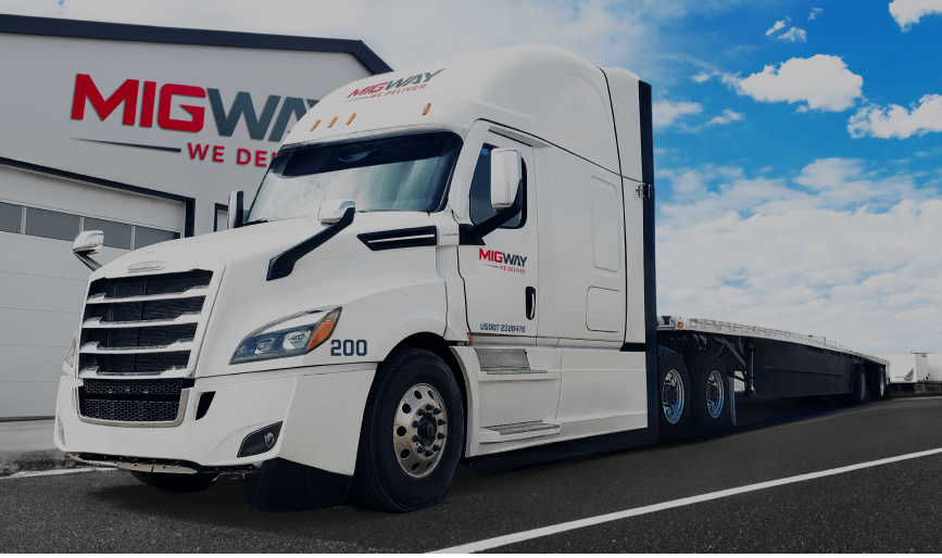 White MigWay semi-truck with flatbed trailer parked outside the terminal
