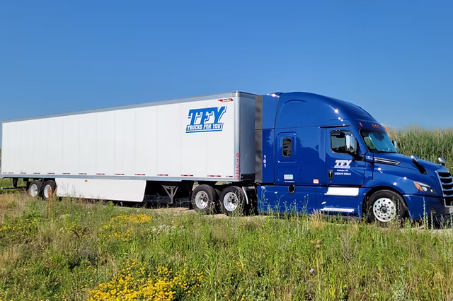 Blue Trucks For You semi-truck with white trailer parked on grass