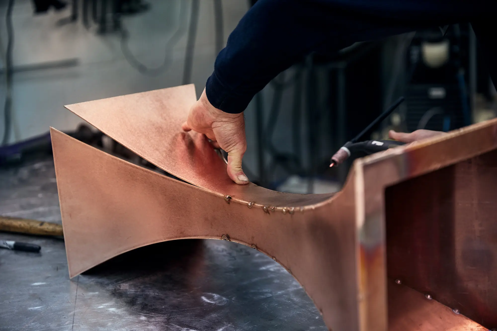 Tom Faulkner workshop craftsman shaping a copper piece by hand