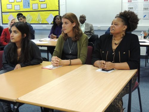 A group of three women sitting at a table listening intently to someone who is off camera.