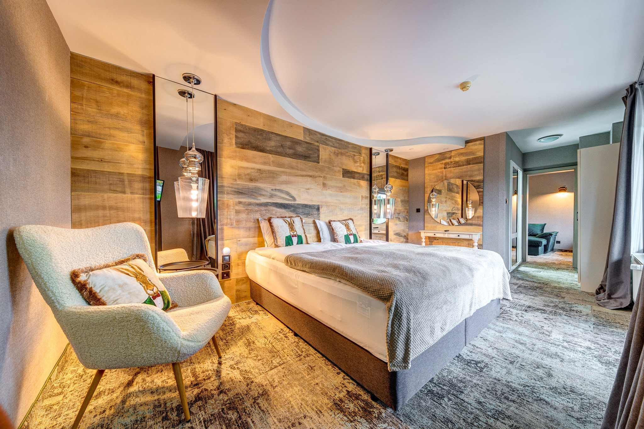 Уютна спалня в апартамент в Гранд Хотел Мургавец с голямо легло с дървена табла, меко осветление и елегантни завеси в зелено и златисто.