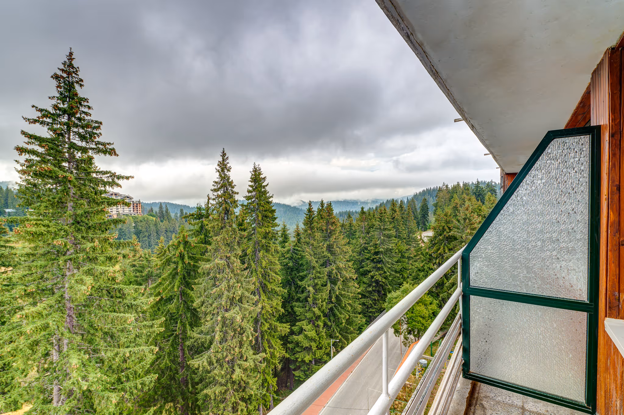 Удобен кът за сядане в двойна стая Standard в Гранд Хотел Мургавец, включващ бежов фотьойл, нощно шкафче и елегантни завеси за релаксираща атмосфера.