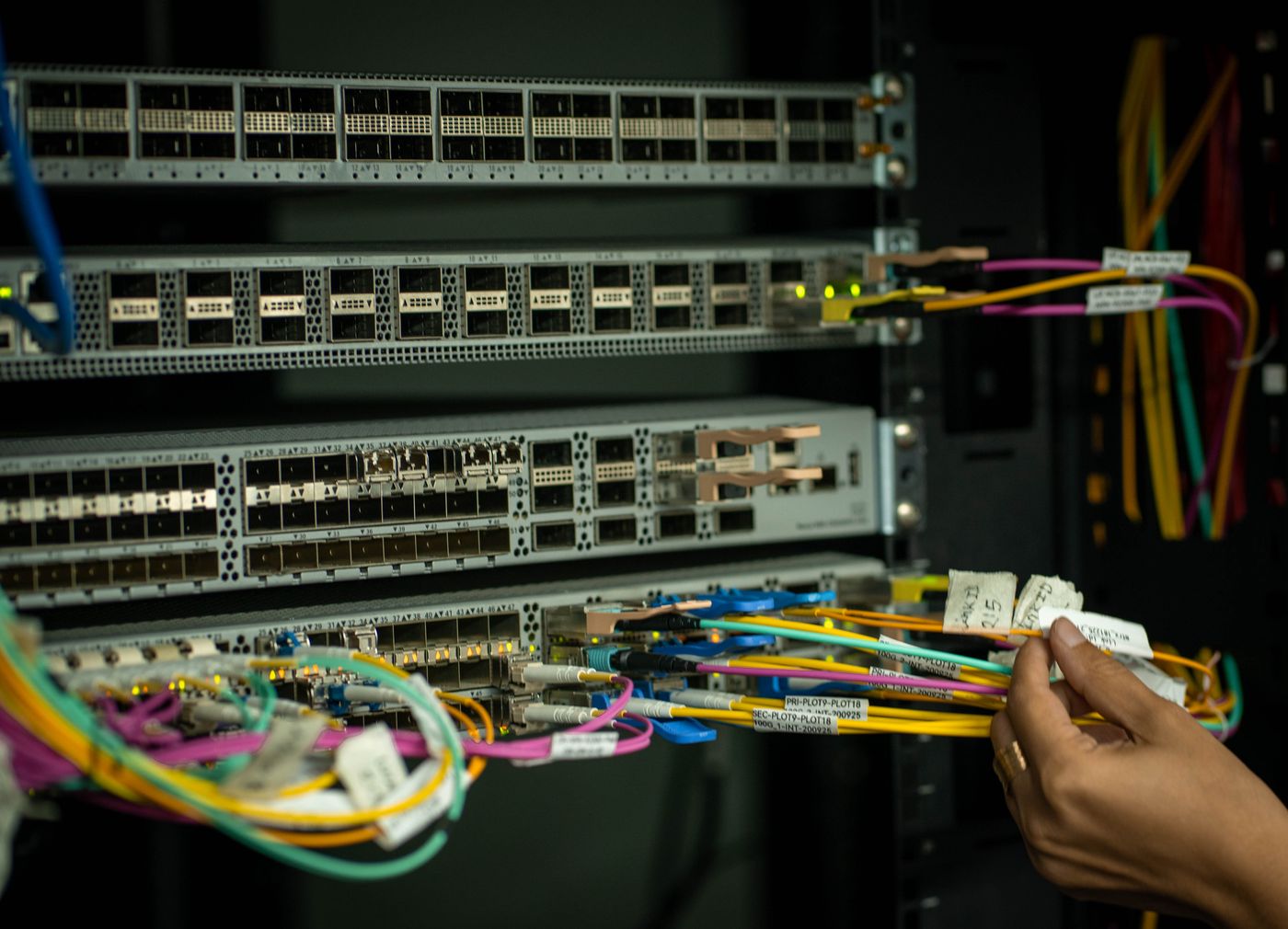 Technician organizing color-coded fiber patch cables in a network rack
