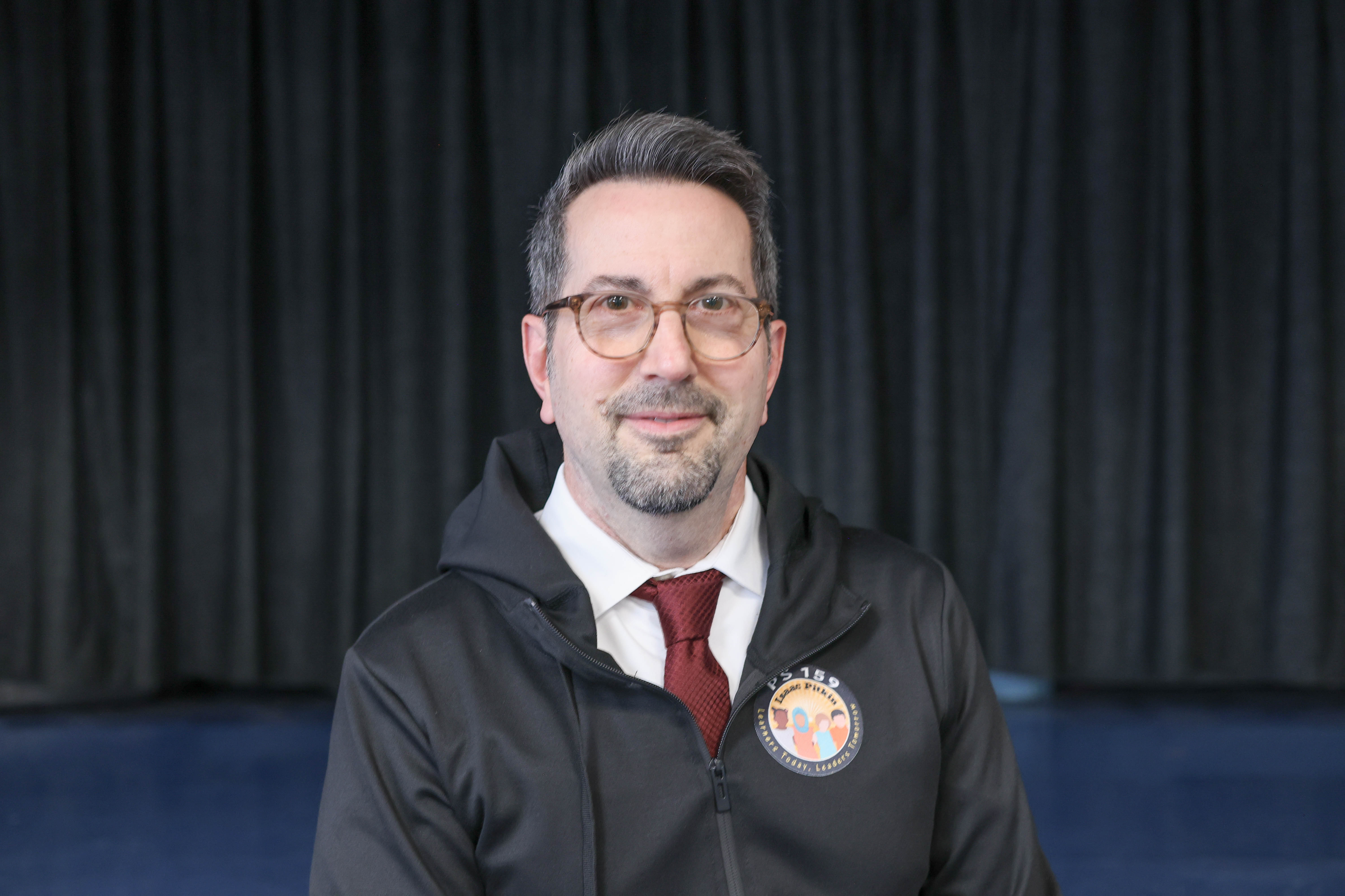 Richard Martello smiling wearing PS 159 school jacket and tie
