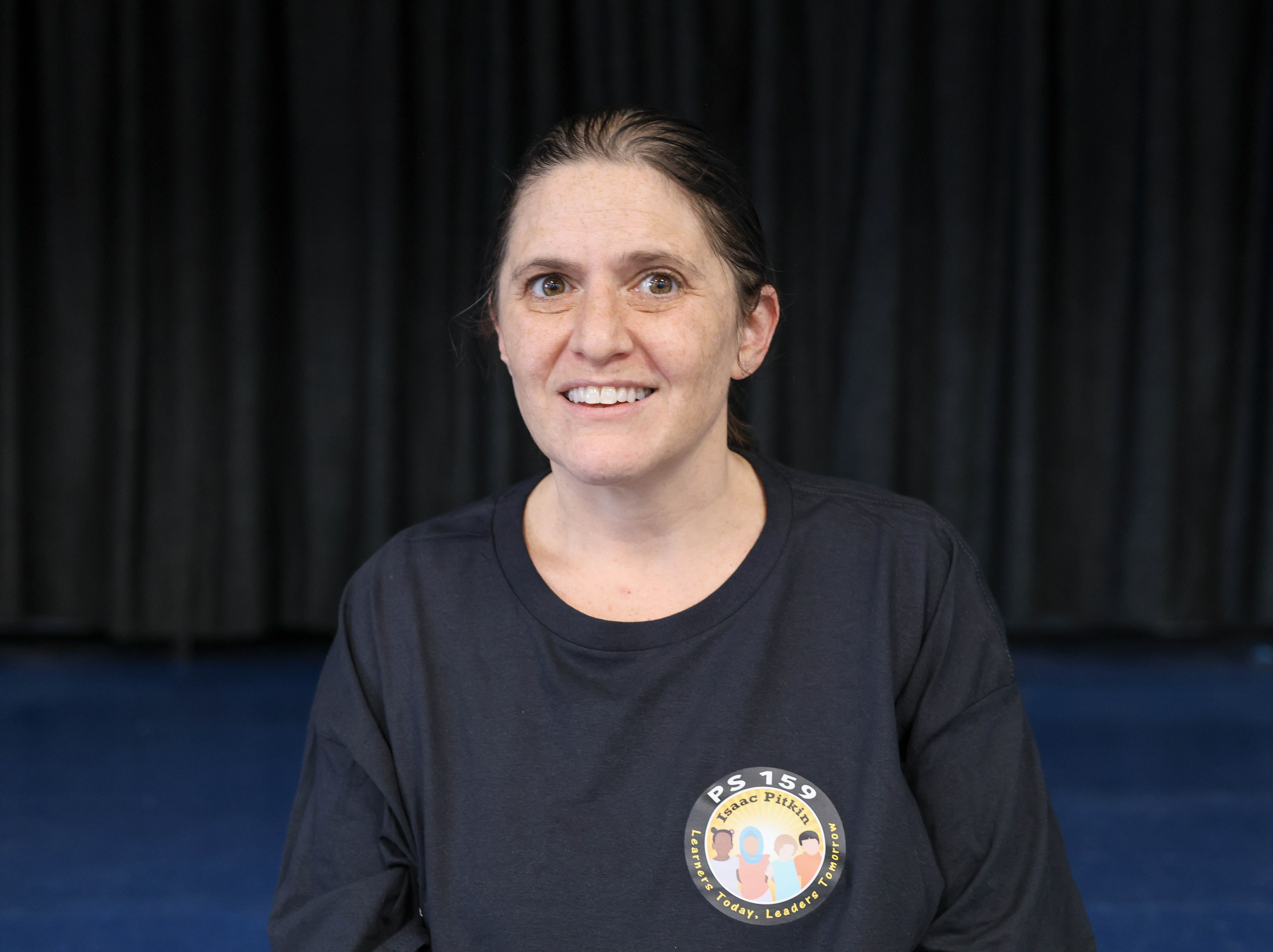 Melanie Wishy smiling wearing a PS 159 Isaac Pitkin school shirt