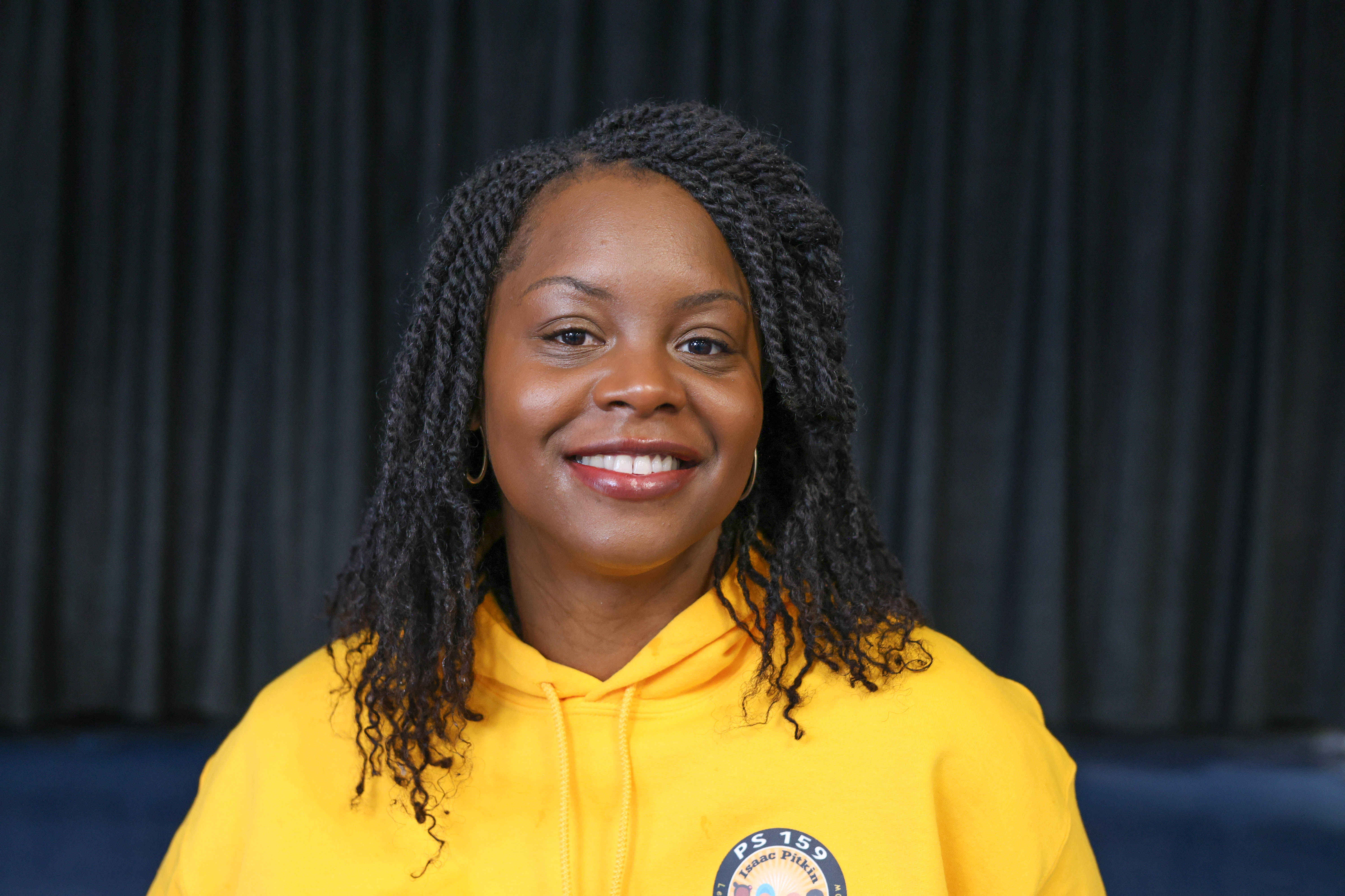 Neffertiti Lee smiling in a PS 159 yellow school hoodie