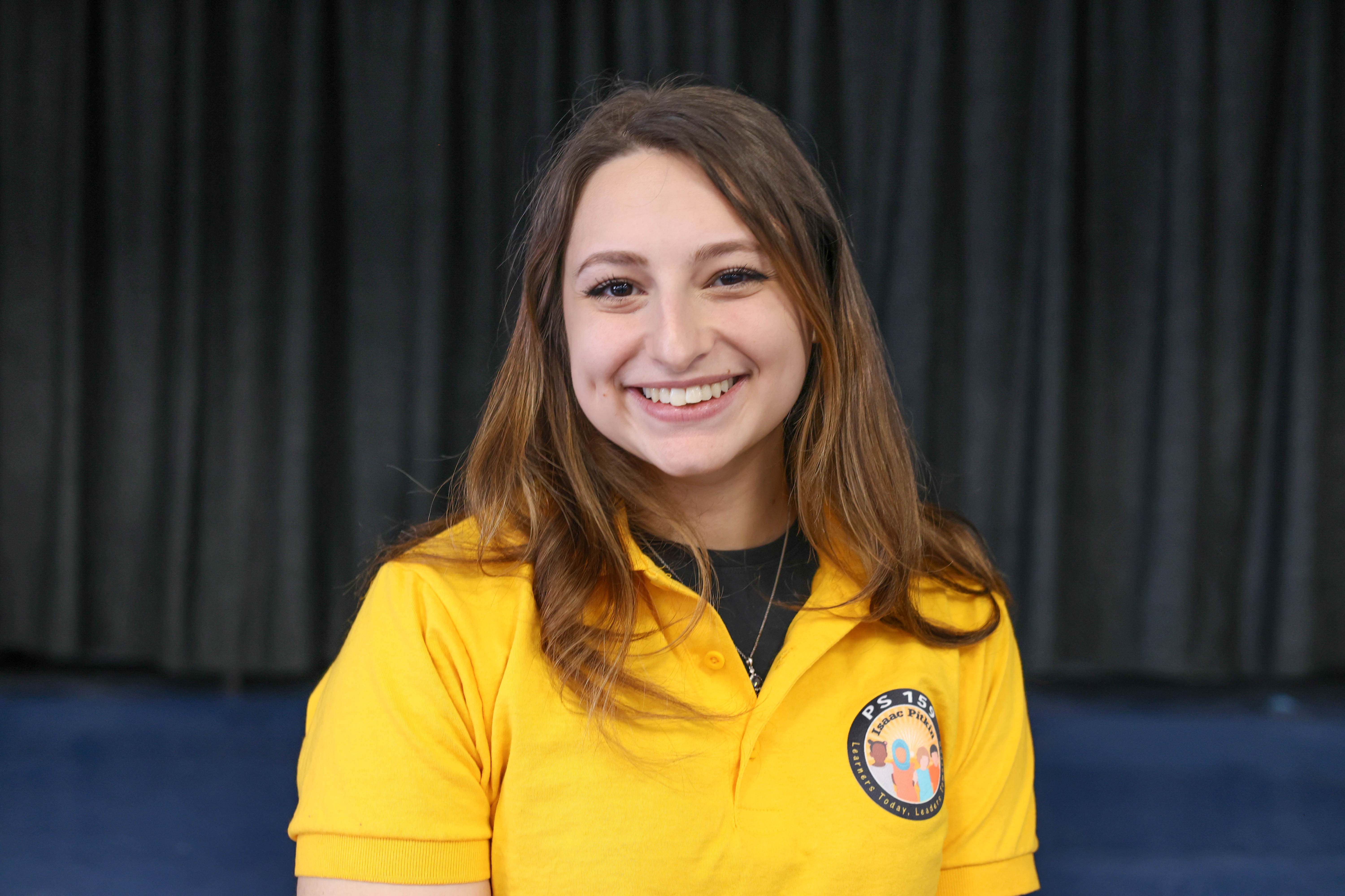 Shaina Steir smiling in PS 159 yellow uniform polo shirt