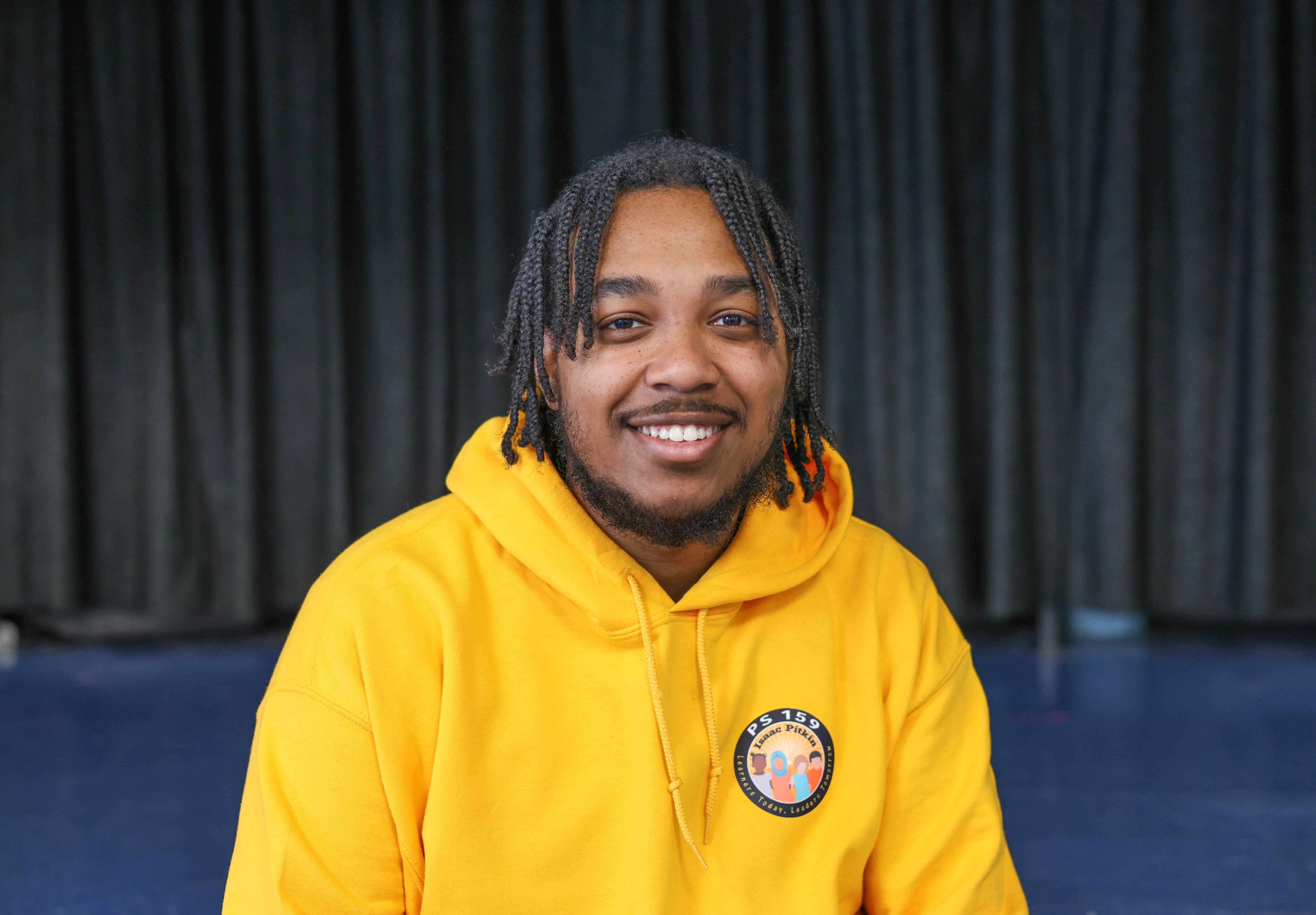Shamar Codrington smiling in a PS 159 yellow school hoodie