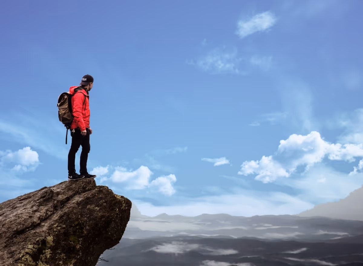 person standing on a rock looking at mountains