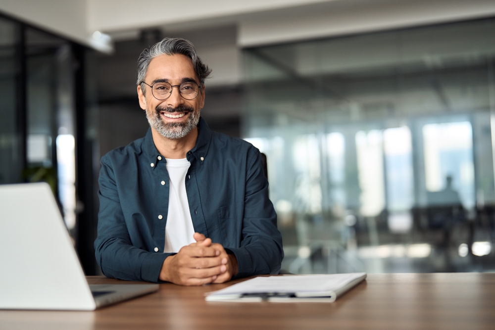 A man with glasses is at a desk, using a laptop, embodying a professional and focused work environment.