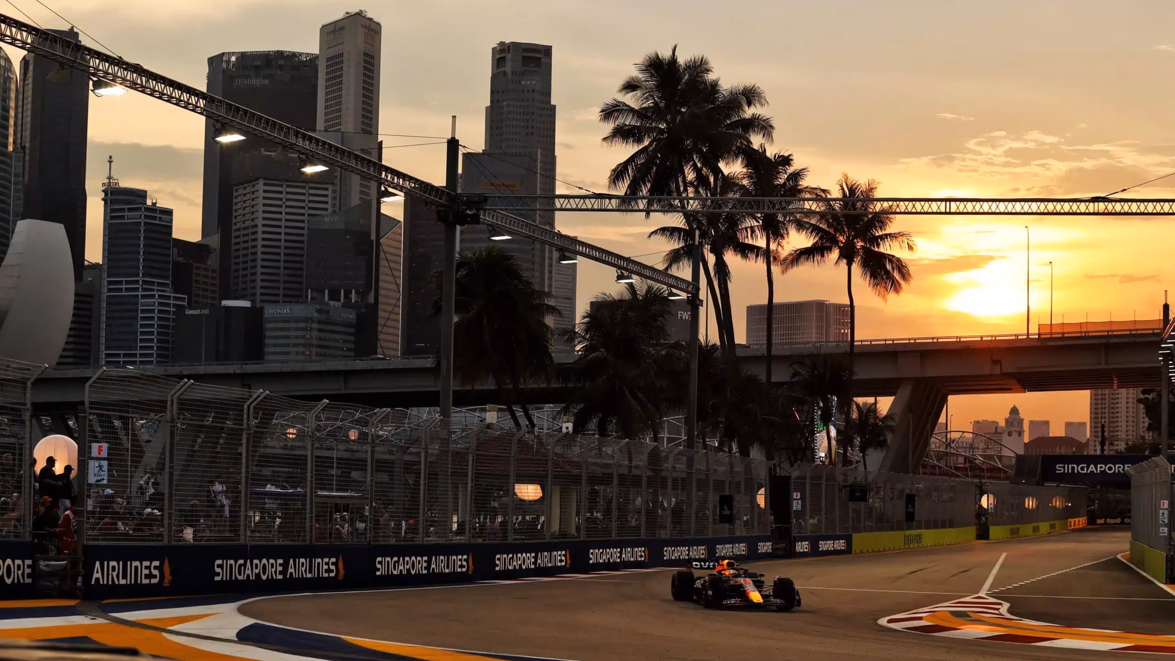 An F1 car speeding along the illuminated Marina Bay Street Circuit with skyscrapers and city lights in the background.