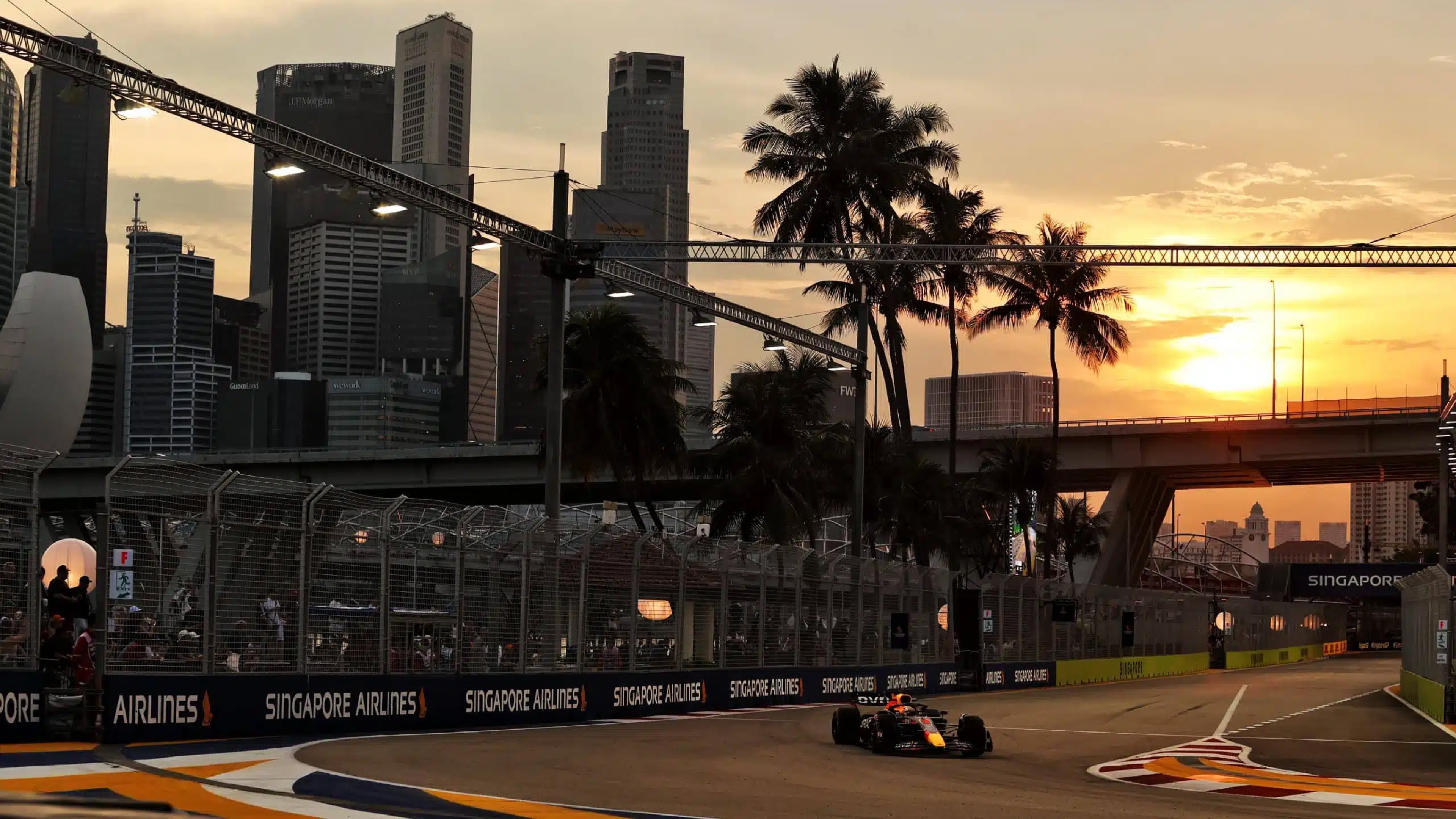 An F1 car speeding along the illuminated Marina Bay Street Circuit with skyscrapers and city lights in the background.