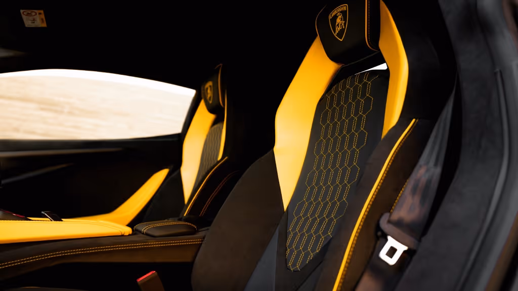 Interior view of the Lamborghini Revuelto's sport seats, upholstered in black and bright yellow Alcantara with contrasting yellow honeycomb stitching and piping.
