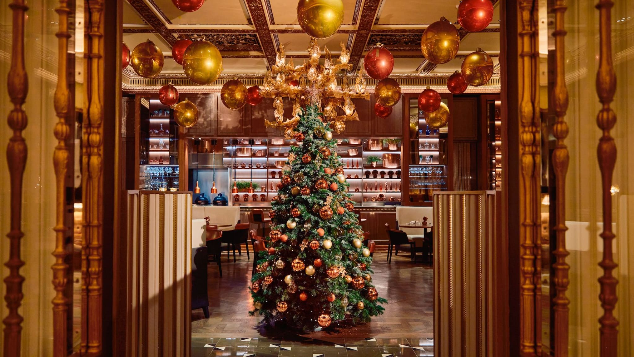 Luxurious Dorchester Promenade at Christmas with gilded pillars and festive trees, set for the legendary afternoon tea.