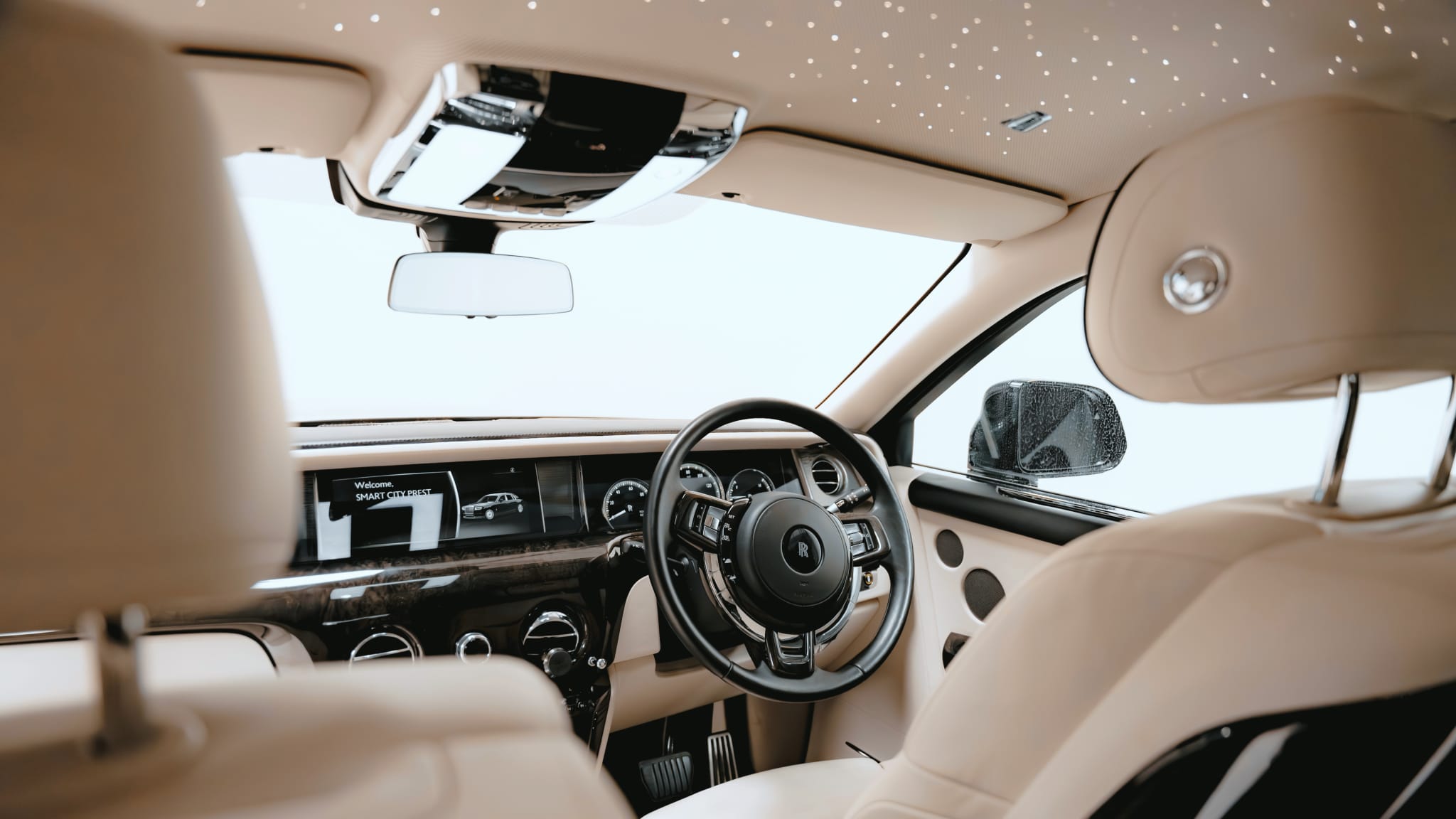 Interior view from the back seat of a Rolls-Royce Phantom, showing the dashboard, steering wheel, and the "Starlight Headliner" ceiling.