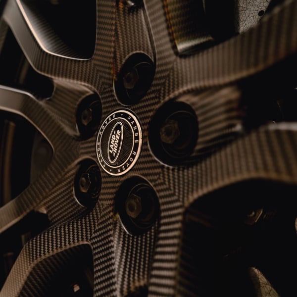 An extreme close-up showcasing the intricate woven texture of the Range Rover Sport SV's lightweight carbon fibre wheel and the distinct Land Rover logo on the centre cap.