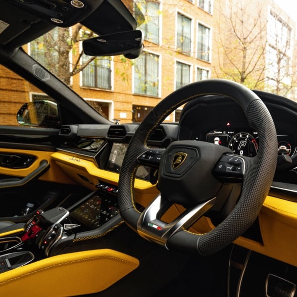 Front interior of a Lamborghini Urus showing the steering wheel and luxury cockpit design.