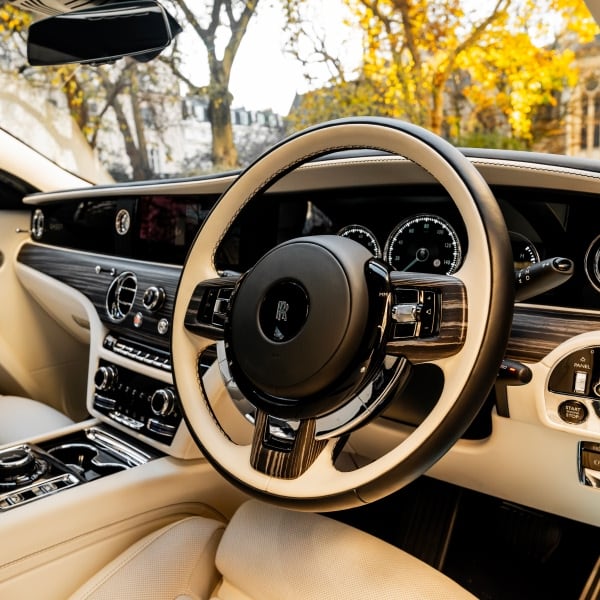 Driver's cockpit of the Rolls-Royce Ghost, showing the modern steering wheel, digital dashboard, and intuitive controls. Empowering our professional chauffeurs with advanced technology for the smoothest, safest executive journey.