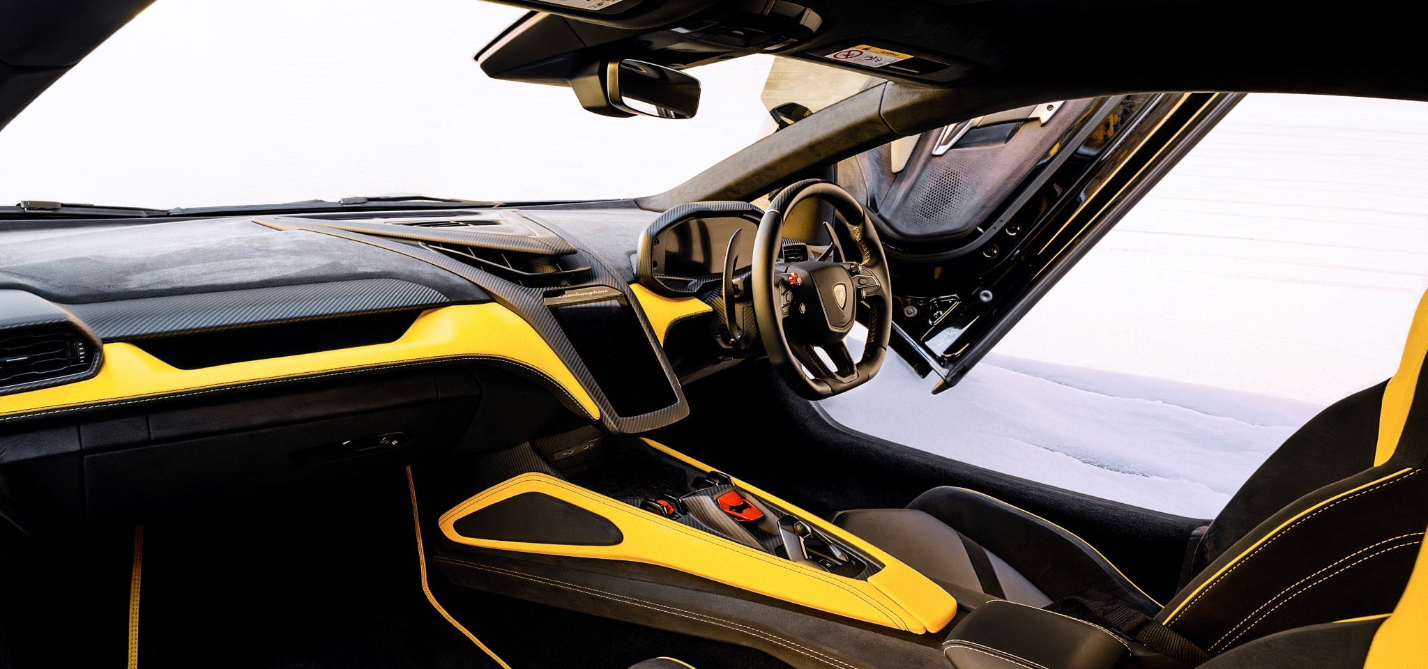 The interior cabin of a yellow and black Lamborghini Revuelto with the scissor door open, highlighting the digital dashboard and Y-shaped design motifs mentioned in the article.