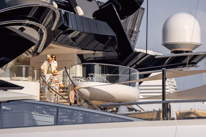 Guests descending a staircase on a large, modern luxury yacht, showcasing LLC's support at high-profile events like the Monaco Yacht Show.