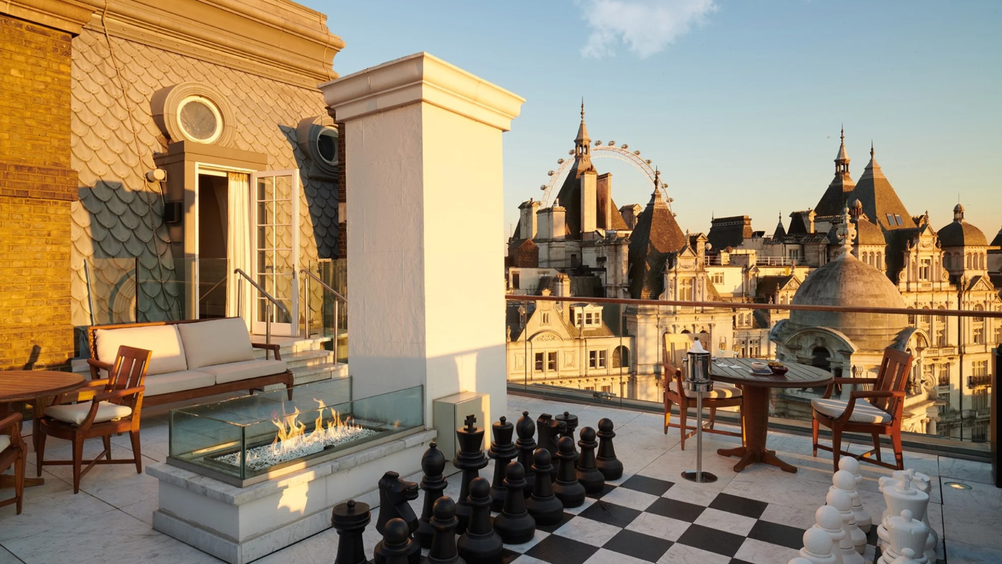 A sprawling rooftop terrace featuring a giant chess set, a glass fire pit, and an unobstructed 180-degree view of the London Eye and Whitehall skyline.