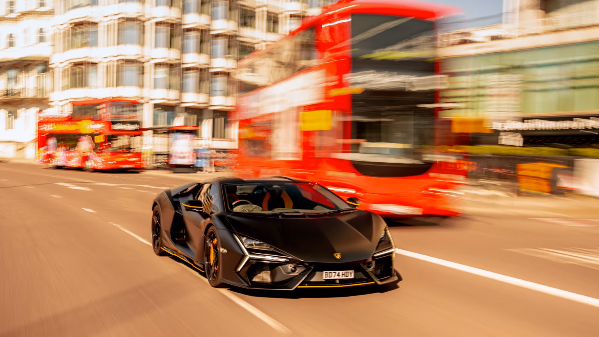 A matte black Lamborghini Revuelto supercar accelerating through London, with the motion blur of a red double-decker bus capturing the energy of a “Supercar Escape”.