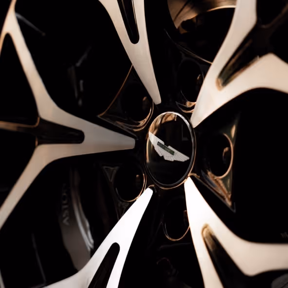 A detailed close-up of the Aston Martin DB11 Volante alloy wheel featuring the Aston Martin center cap, multi-spoke wheel design, and high-performance brake components.