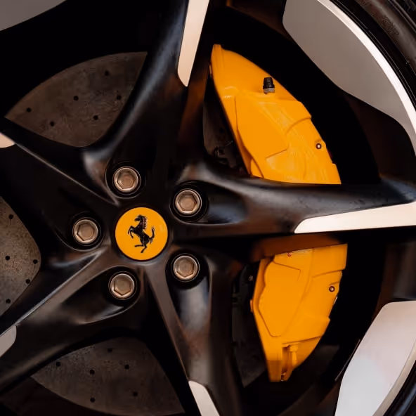 A macro shot of the black Ferrari Purosangue wheels featuring the iconic yellow Giallo Modena brake calipers and the Prancing Horse center cap.