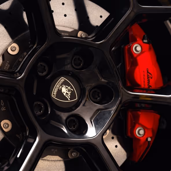 A macro shot of the black alloy wheels on a Lamborghini Temerario, highlighting the high-performance carbon-ceramic brake discs and bold red brake calipers.