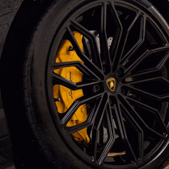 Detailed view of a Lamborghini Urus black alloy wheel with yellow brake calliper.