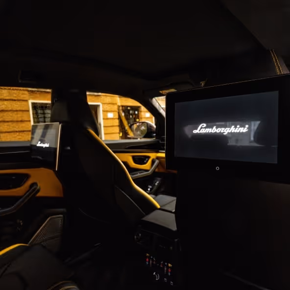 Rear interior of a Lamborghini Urus featuring premium leather seats and rear entertainment screens.
