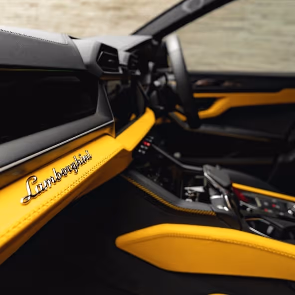 Close-up of the Lamborghini Urus dashboard showcasing yellow interior trim and luxury detailing.