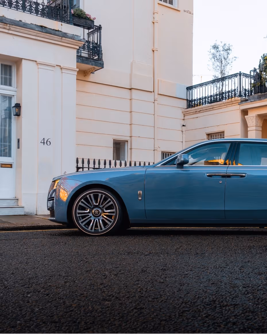 Side view of the LLC Rolls-Royce Ghost showcasing its long, commanding silhouette and high-gloss wheel detailing on a quiet, affluent London street.