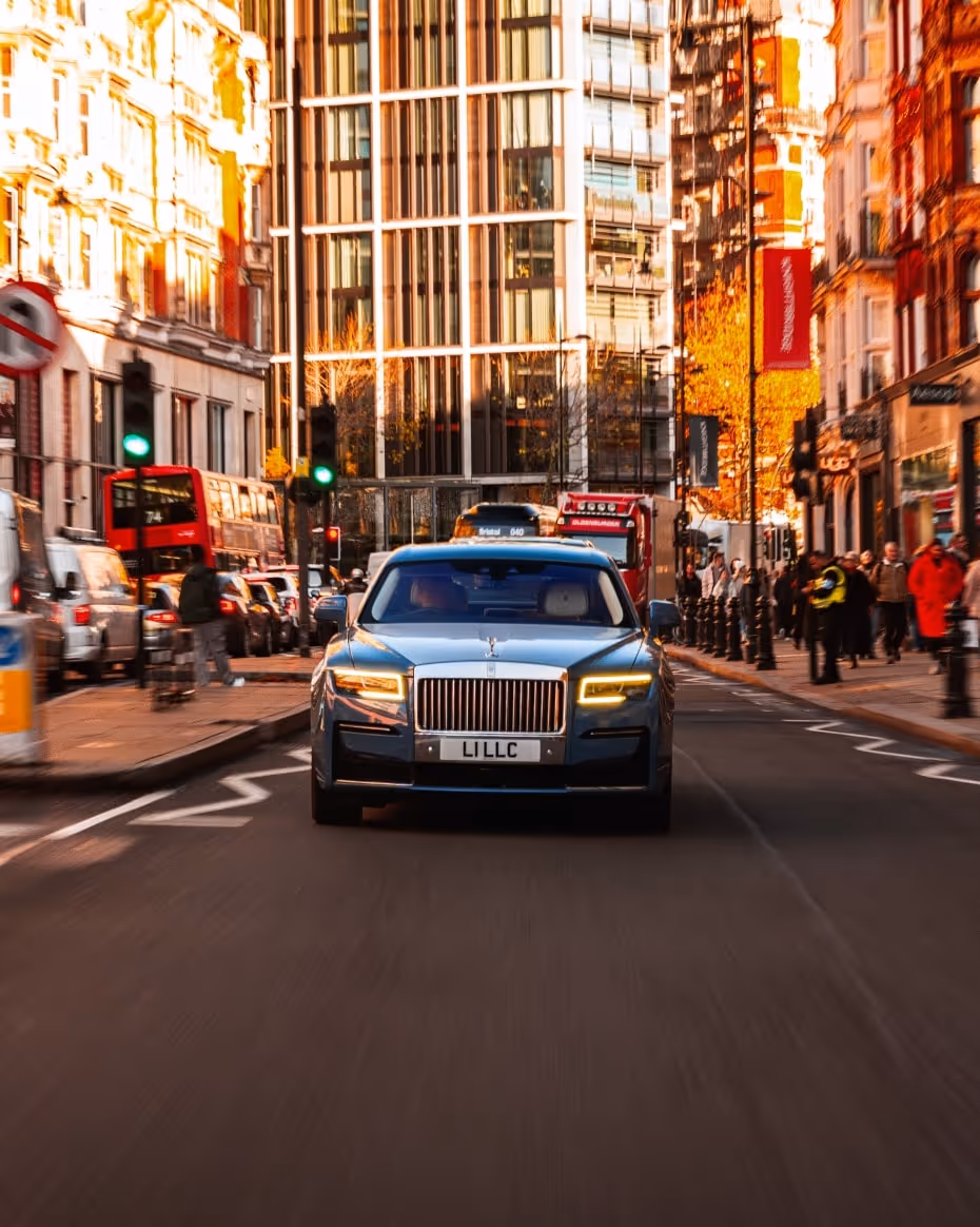 Side view of the LLC Rolls-Royce Ghost showcasing its long, commanding silhouette and high-gloss wheel detailing on a quiet, affluent London street.
