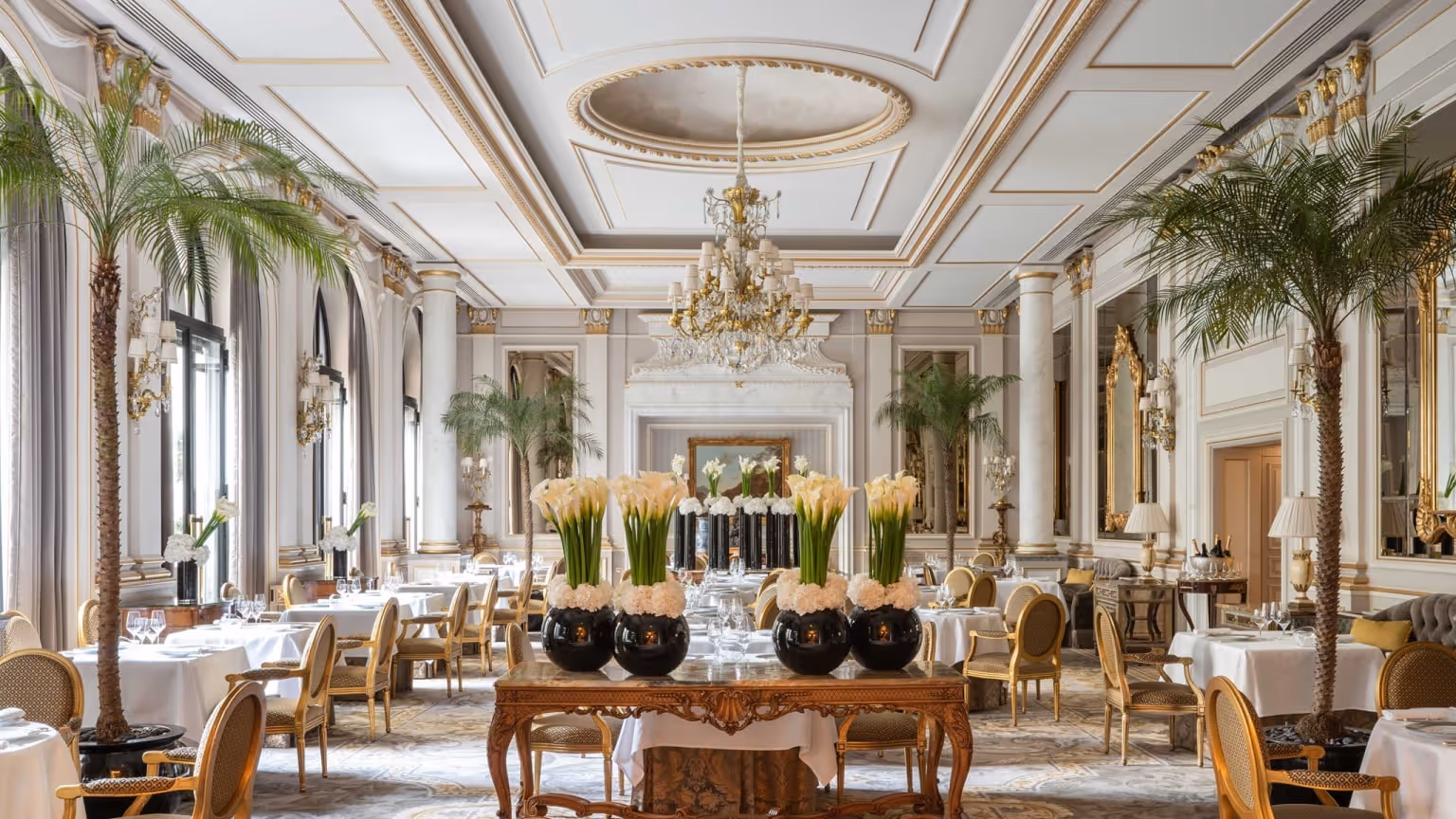 Elegant dining room at Le Cinq restaurant inside Four Seasons Hotel George V Paris, featuring crystal chandeliers, classical French interiors and luxury table settings.