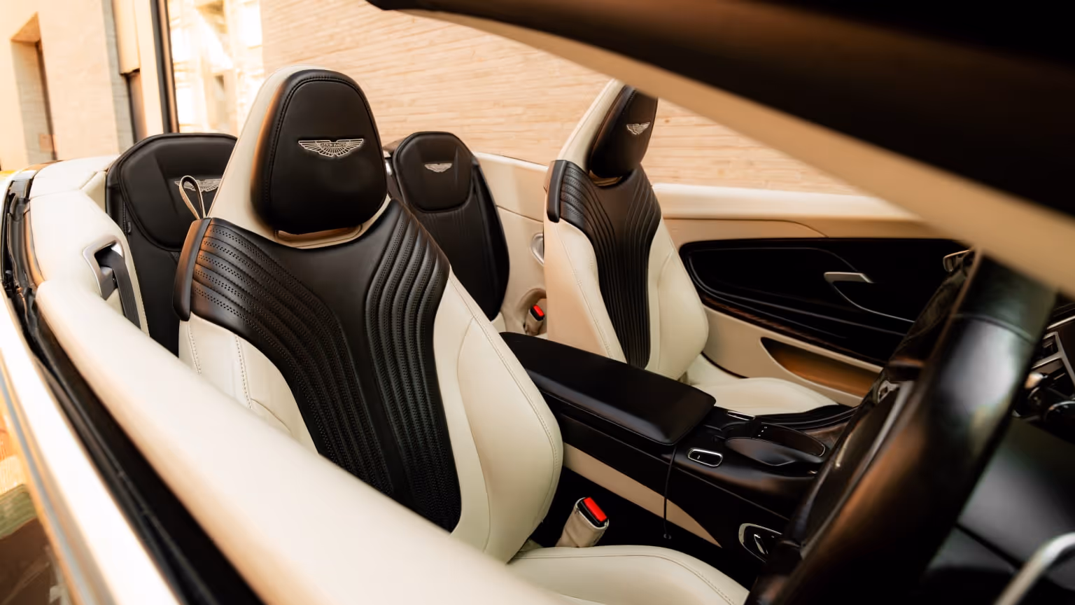 Luxury convertible car interior with black-and-cream leather seats, viewed from the driver’s side during a self-drive experience in warm evening light.