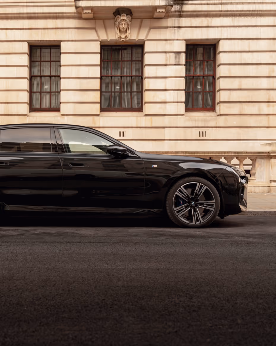 Side profile of a long-wheelbase BMW 7 Series chauffeur car with rear privacy glass.