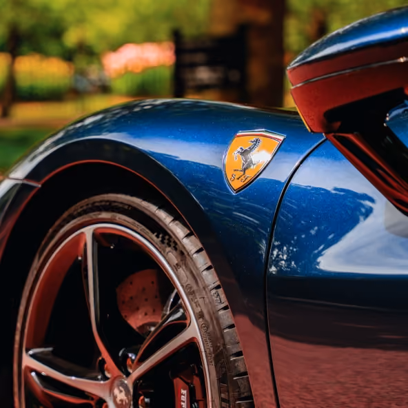 Close-up of the Ferrari 296GTB front fender featuring the Ferrari Shield badge, front wheel, brake caliper, and sculpted bodywork.