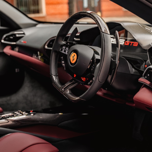 The driver’s cockpit of the Ferrari 296GTB featuring the signature steering wheel, digital instrument display, and premium leather-trimmed dashboard.