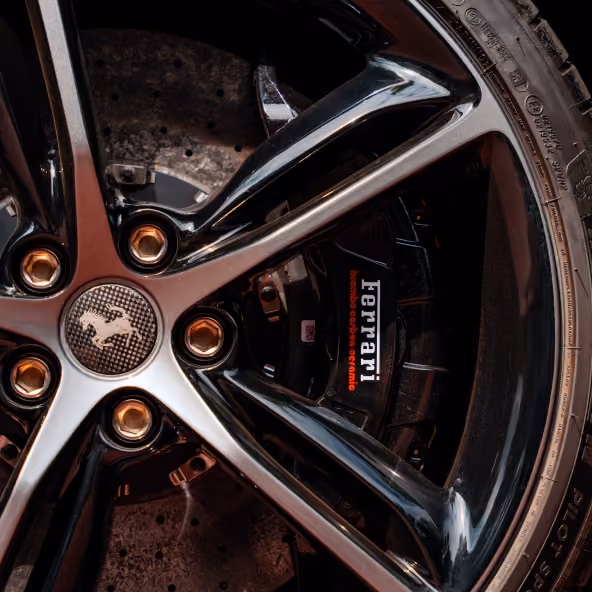 Close-up of the Ferrari 296GTB front alloy wheel, carbon-ceramic brake disc, and Ferrari brake caliper, highlighting the vehicle’s high-performance braking system and premium detailing.