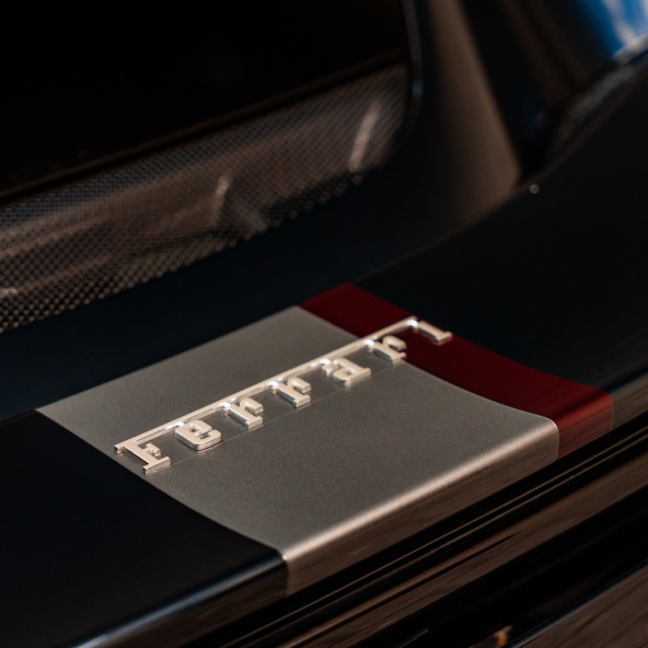 Close-up of the Ferrari 296GTB rear spoiler with the Ferrari badge and Italian tricolour detail.