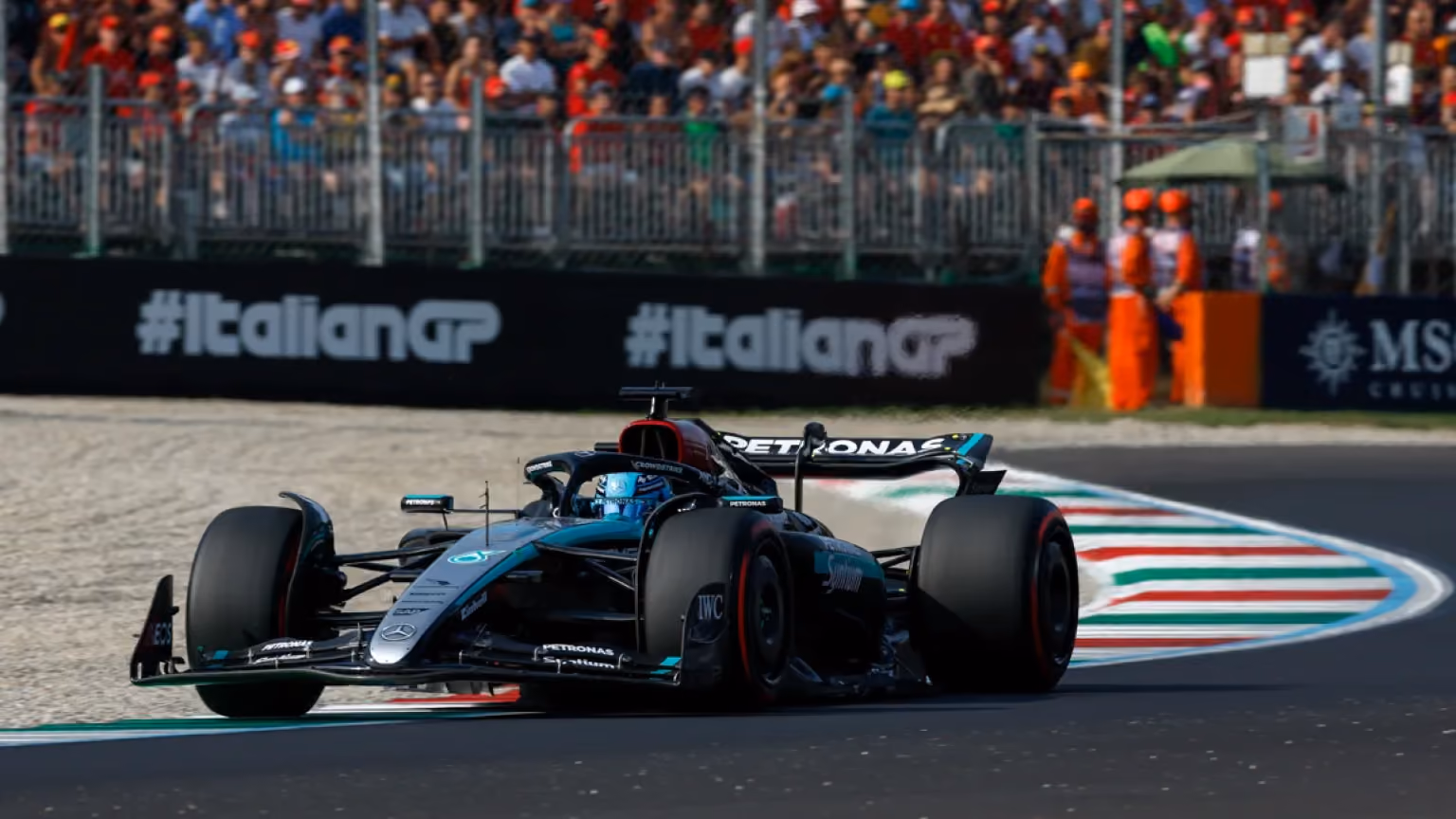Mercedes-AMG Petronas Formula 1 car racing through a corner at the Autodromo Nazionale Monza during the Italian Grand Prix, with spectators in the background.