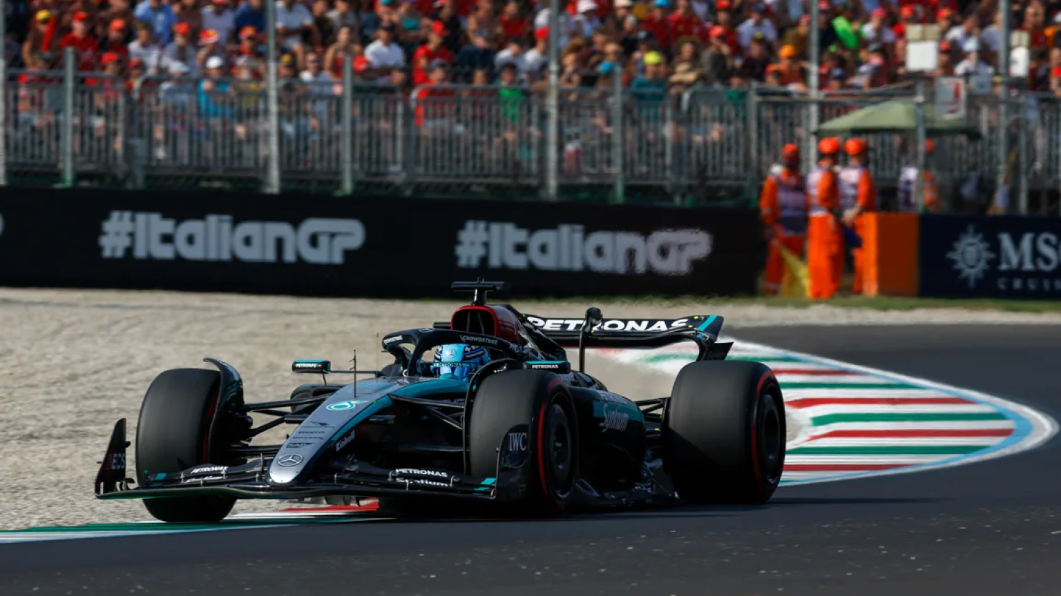 Mercedes-AMG Petronas Formula 1 car racing through a corner at the Autodromo Nazionale Monza during the Italian Grand Prix, with spectators in the background.