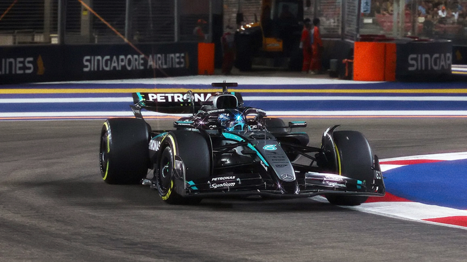 Mercedes Formula 1 racing car driving on the Marina Bay Street Circuit during the Singapore Grand Prix at night.