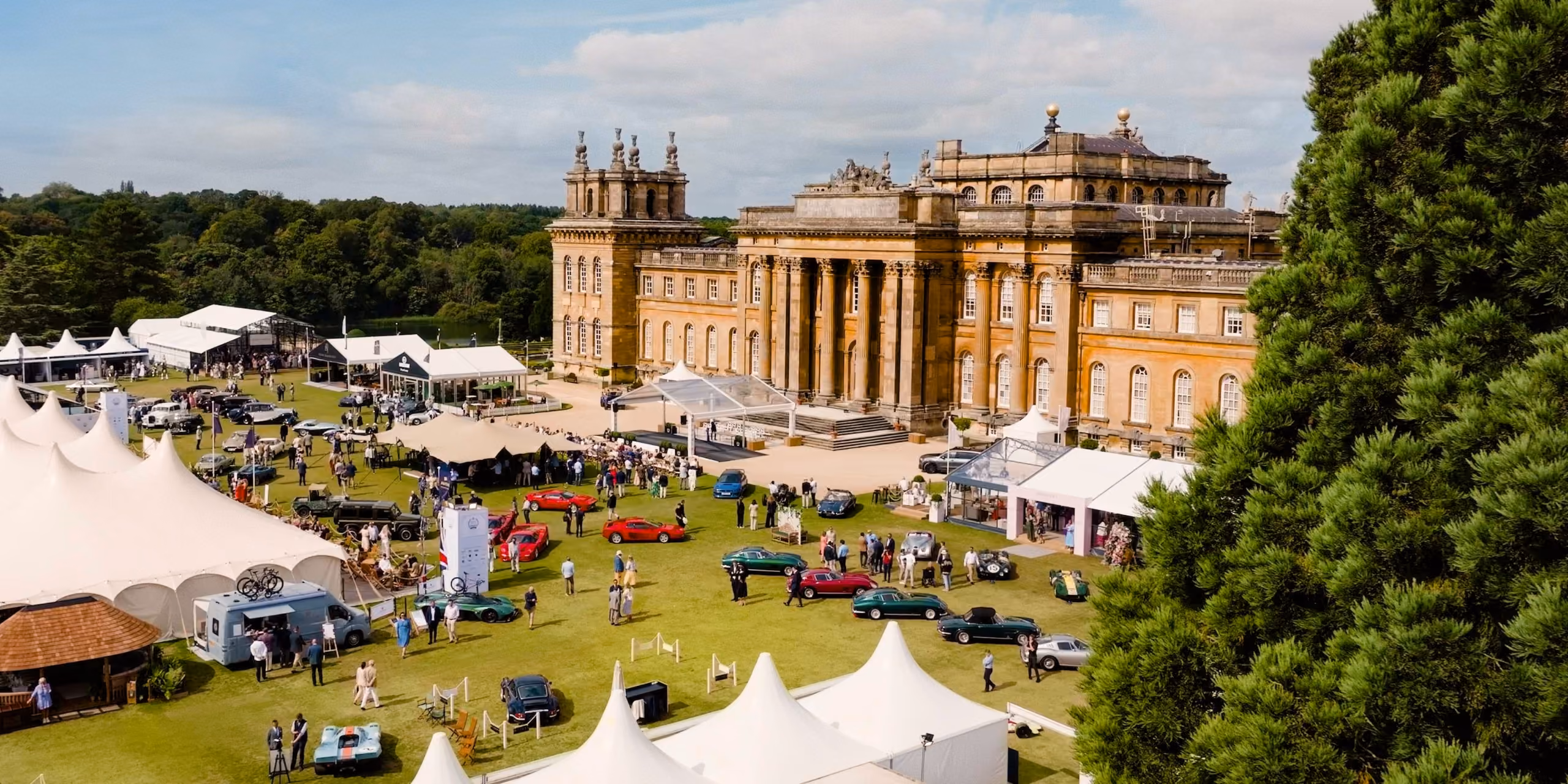 Aerial view of Salon Privé at Blenheim Palace, with classic and luxury cars displayed across the South Lawn, hospitality marquees, guests and the palace in the background.
