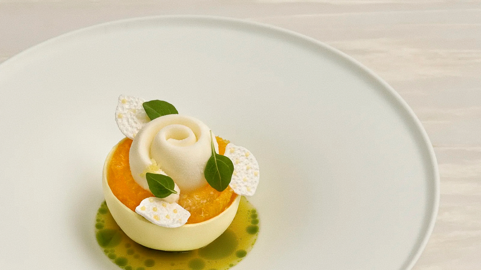 LOULOU Lemon dessert at Odette Singapore, featuring a white meringue shell with Amalfi lemon curd, basil sorbet, citrus segments, green leaves and crisp white garnishes.