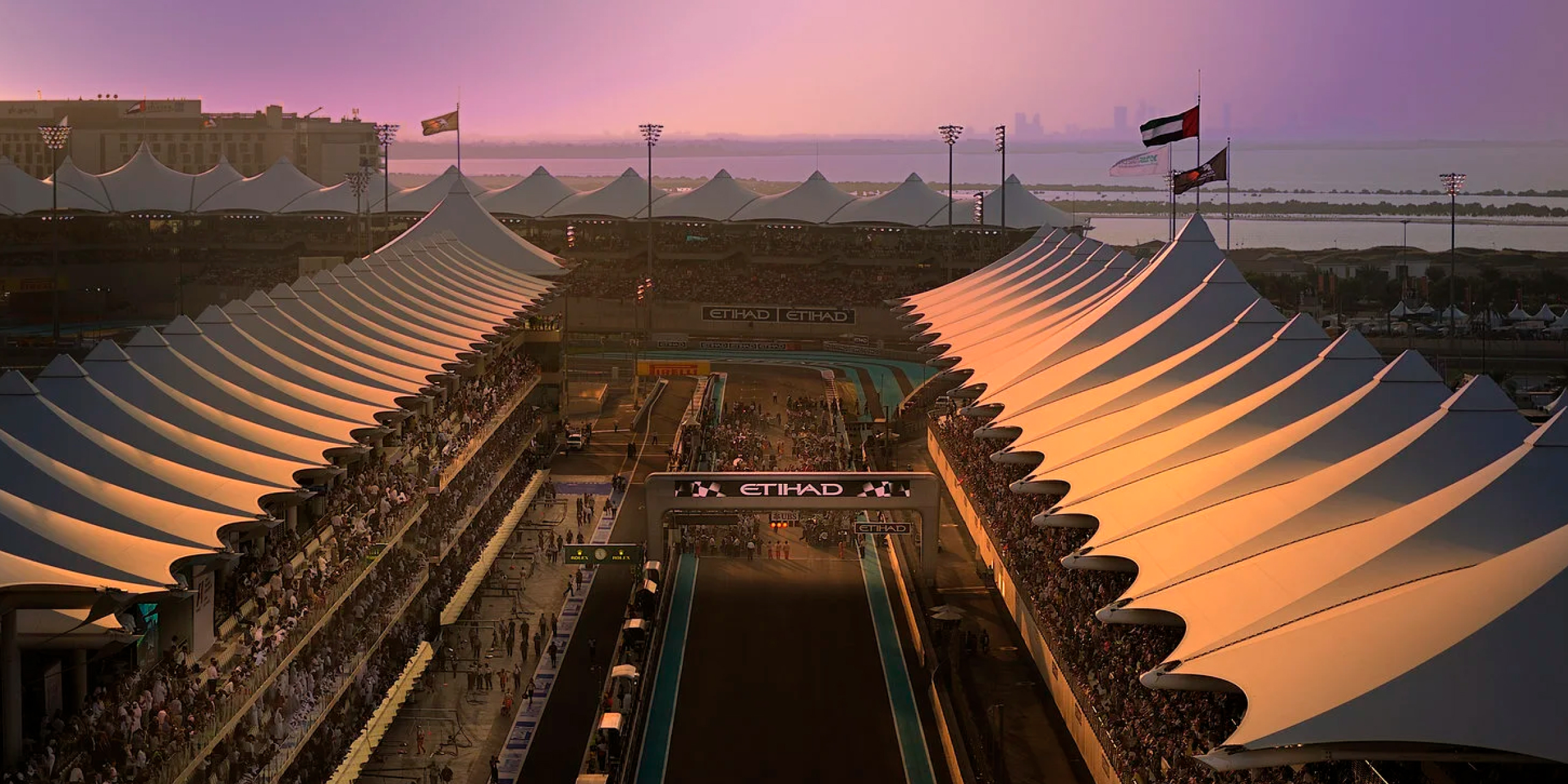 Aerial view of Yas Marina Circuit at twilight during the Abu Dhabi Grand Prix, with packed grandstands and the start-finish straight.